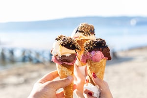friends cheers'ing ice cream cones outside at the beach