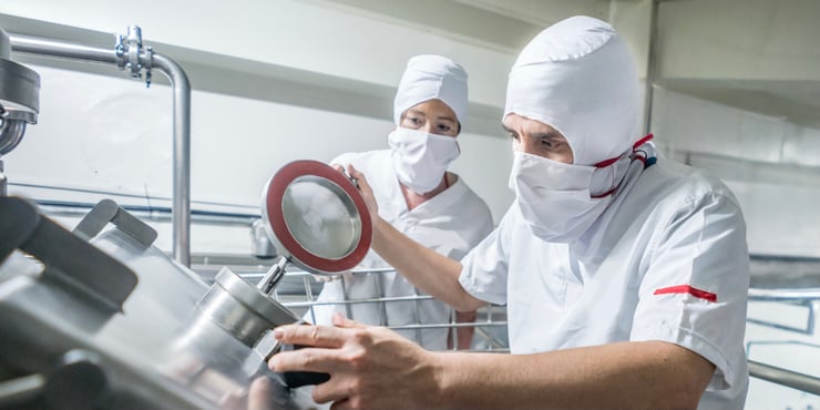Employee examining industrial centrifuge for dairy production