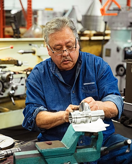 Separators employee inspecting used centrifuge parts